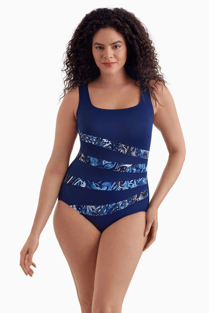 Woman wearing a navy blue one-piece swimsuit with four streaks with a pattern inside