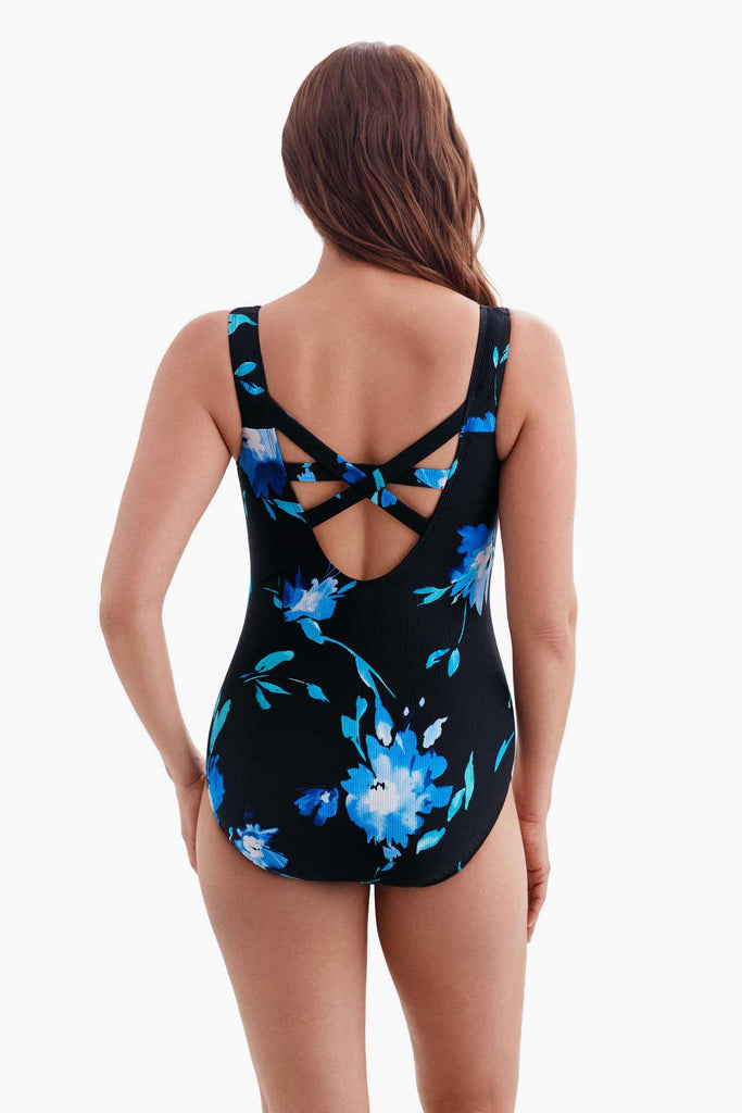 Woman faced away wearing a one-piece swimsuit with a blue floral pattern and X back