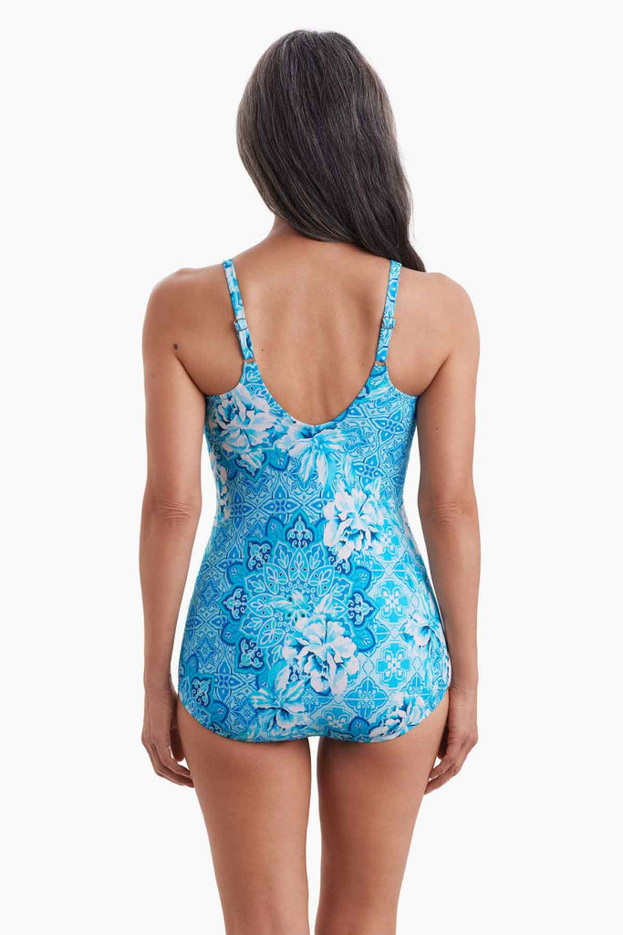 Woman facing away wearing a one-piece swimsuit with a blue abstract print