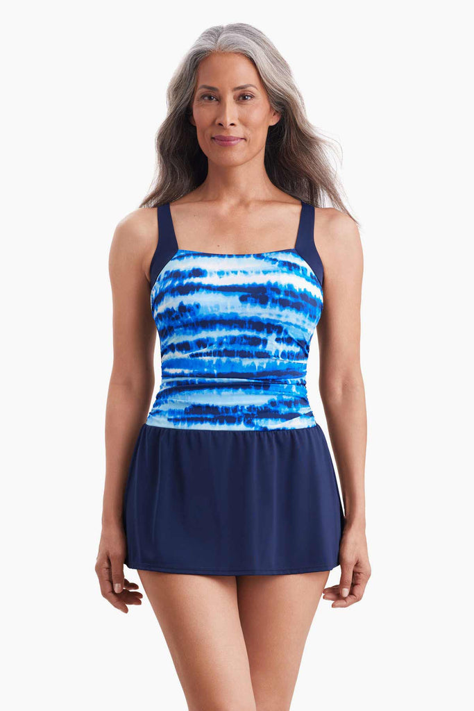 Woman wearing a swim skater dress with a blue tie dye pattern 