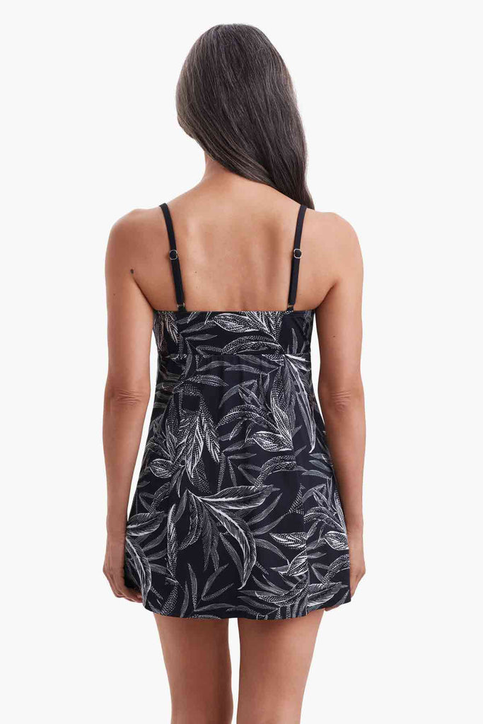 Woman turned away wearing a swim dress with black and white palm leaves