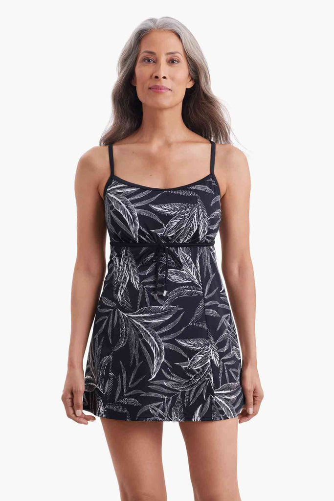 Woman wearing a swim dress with a black and white palm leave print