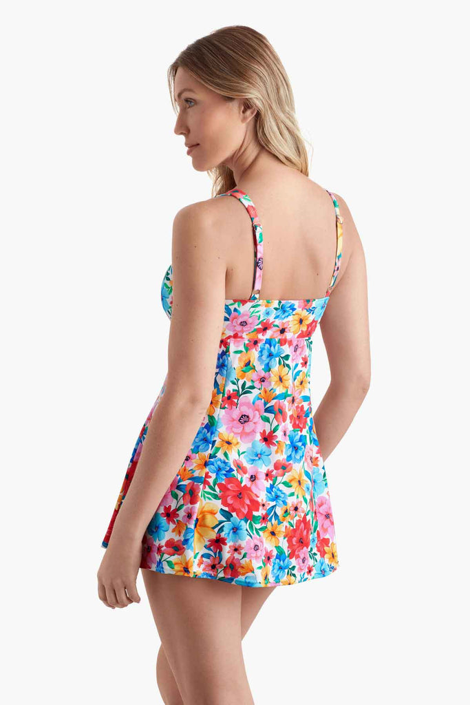 Woman facing left wearing a swim dress with a multicolored floral print