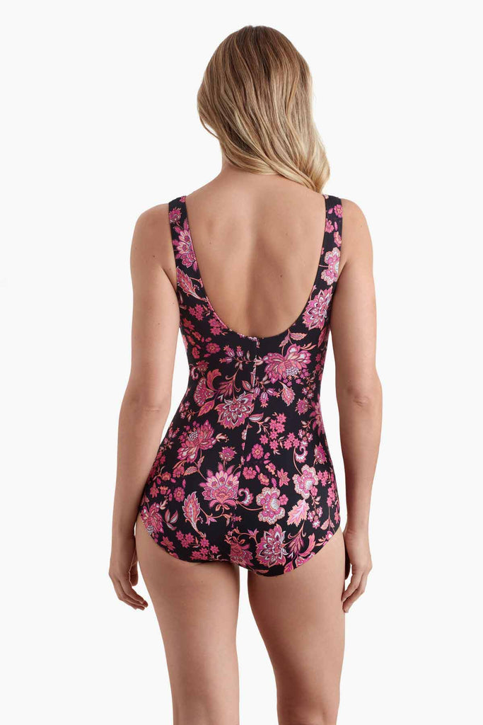 Woman faced away wearing a one-piece swimsuit with a pink and black floral pattern