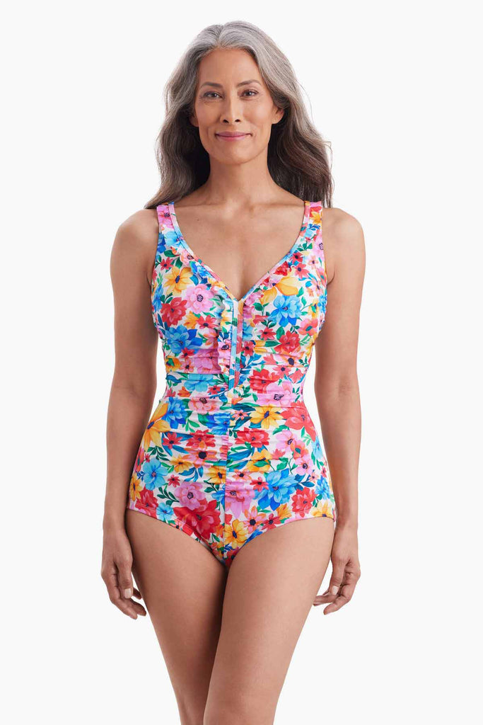 Woman wearing a ruffle front one-piece swimsuit with a multicolored floral print