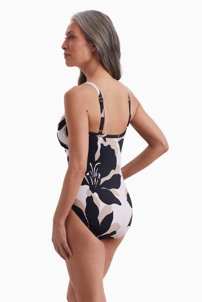 Woman facing left wearing a one-piece swimsuit with a large black and white floral pattern