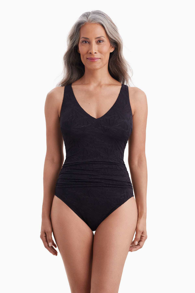 Woman wearing a black one-piece swimsuit with a textured floral print