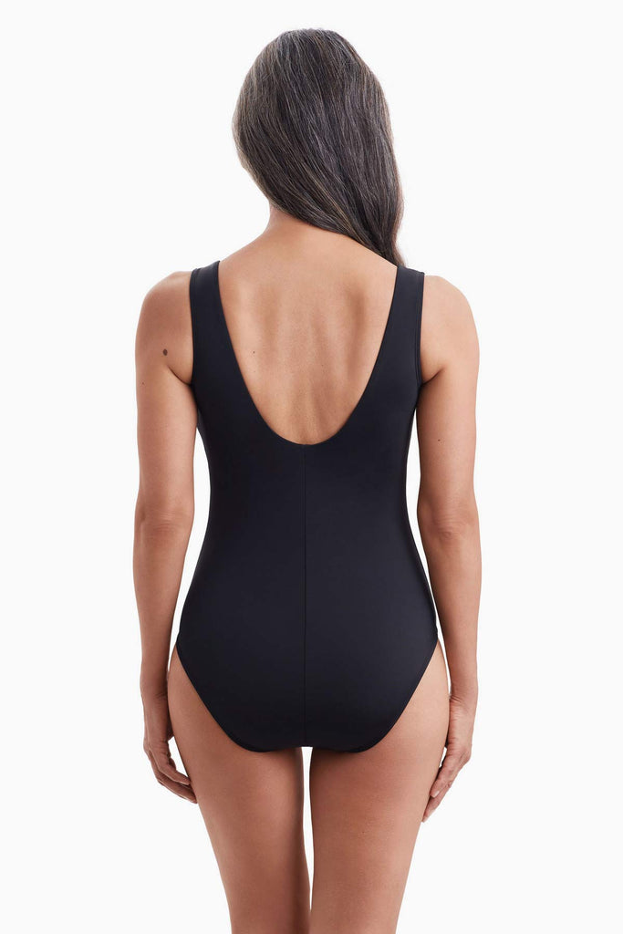 Woman turned away wearing a black one-piece swimsuit 