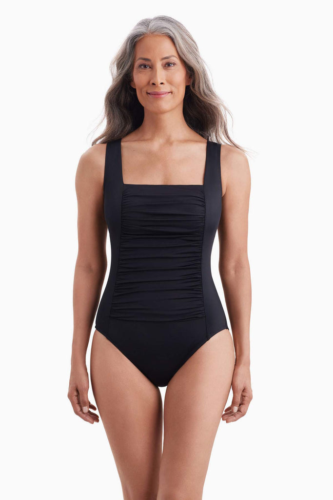 Woman wearing a black one-piece swimsuit with shirring on the front