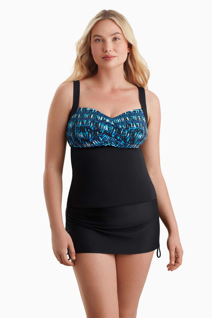 Woman wearing a tankini top with a blue pattern along the bust