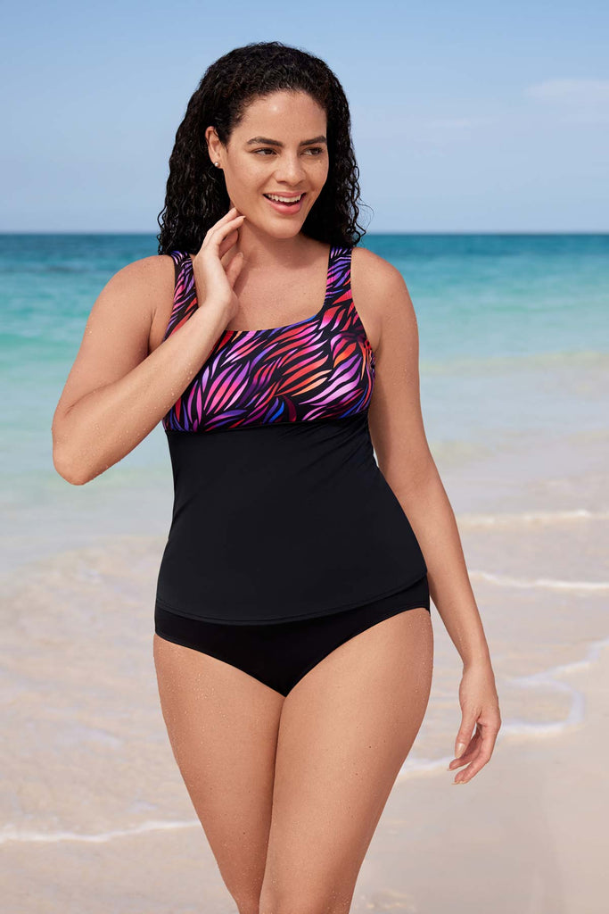 Woman next to beach wearing a tankini swim top with a pink pattern on the bust