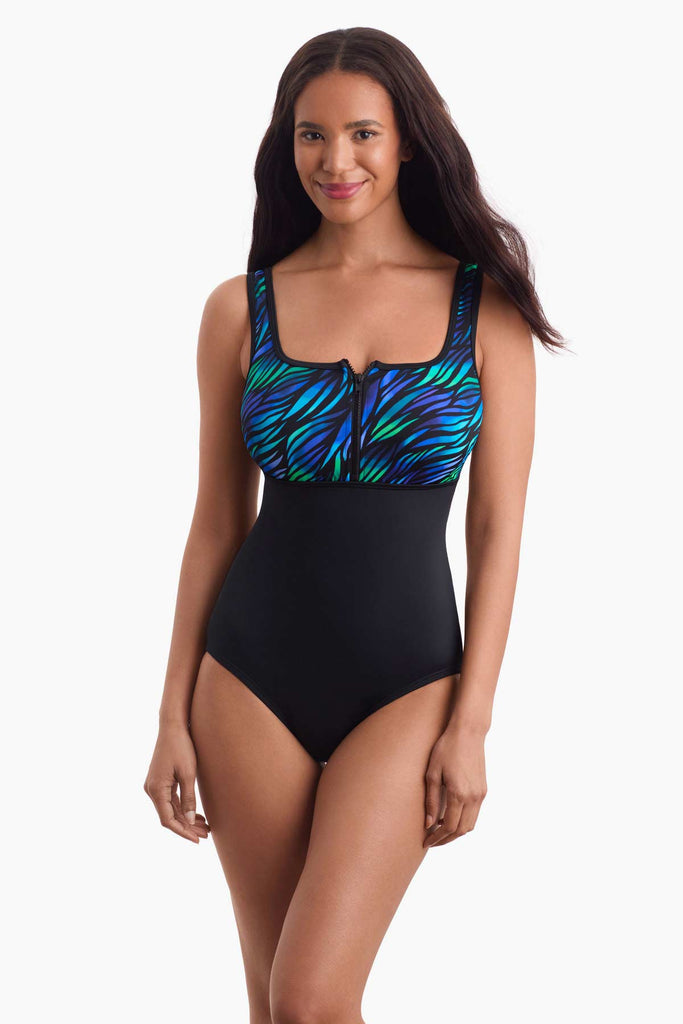 Woman wearing a one-piece swimsuit that is part black and part blue and green pattern