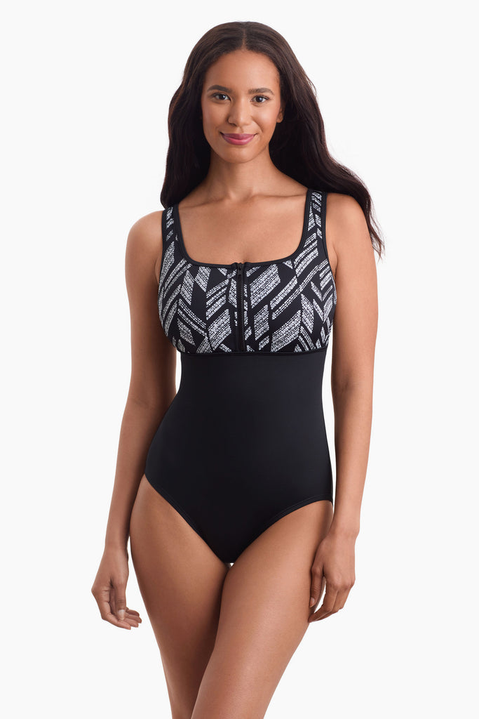 Woman facing forward wearing a one-piece swimsuit with a black and white pattern at the bust