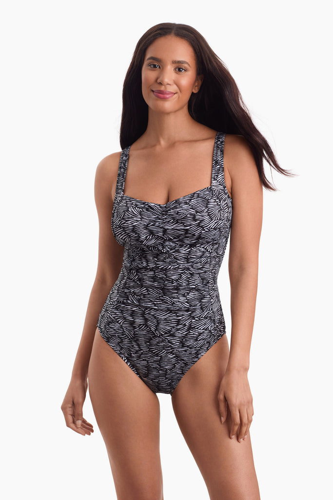 Woman wearing a black and white one-piece swimsuit with an abstract pattern