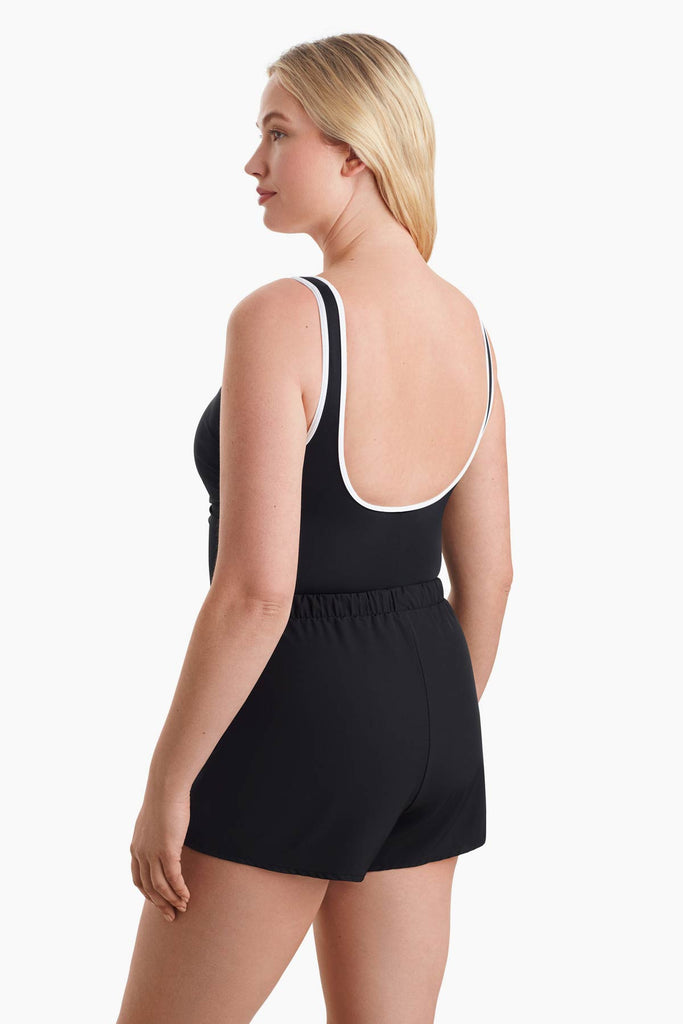 Woman faced left to show detail of white trim of the one-piece swimsuit