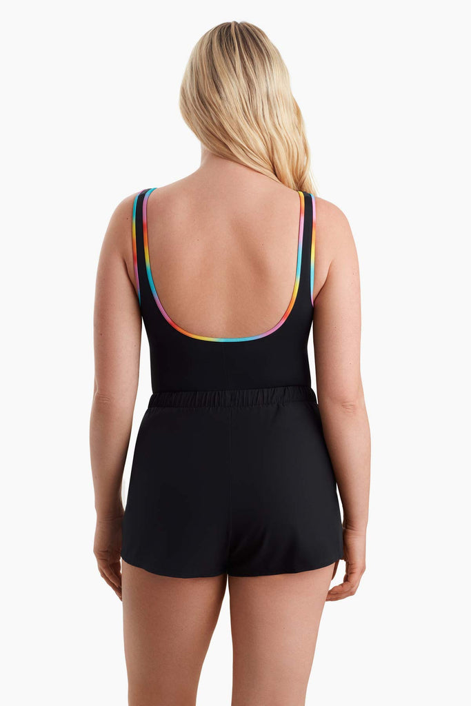 Woman turned away wearing a one-piece swimsuit with rainbow trim on the back