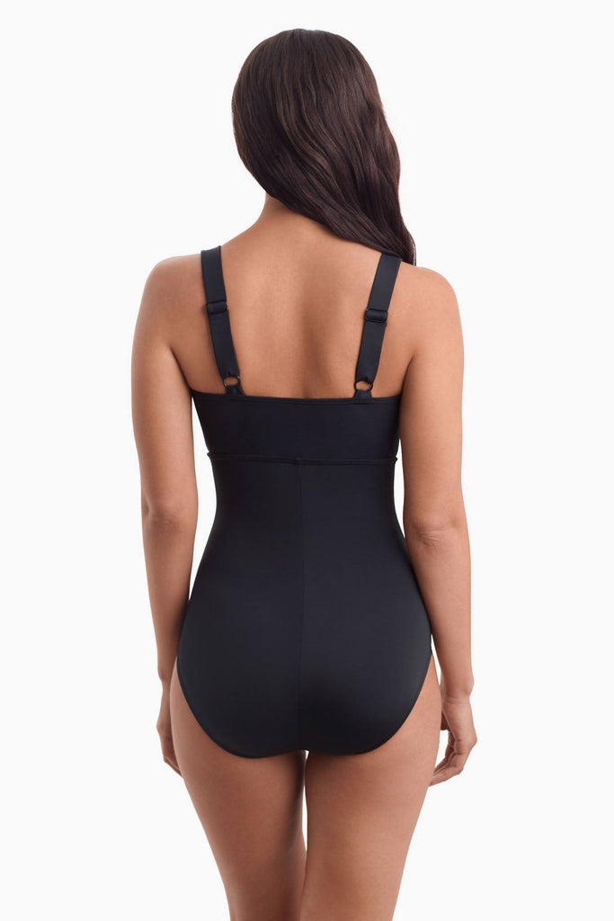 Woman facing away to show back strap detail of one-piece swimsuit