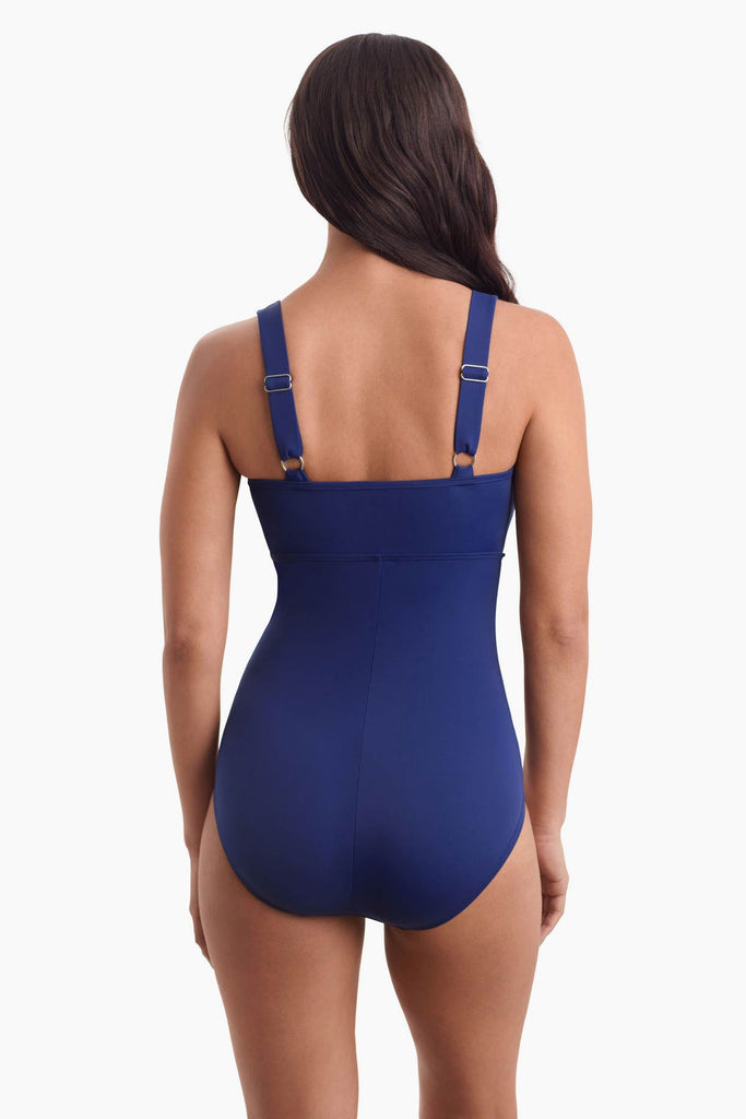 Woman facing away wearing a navy blue swimsuit 