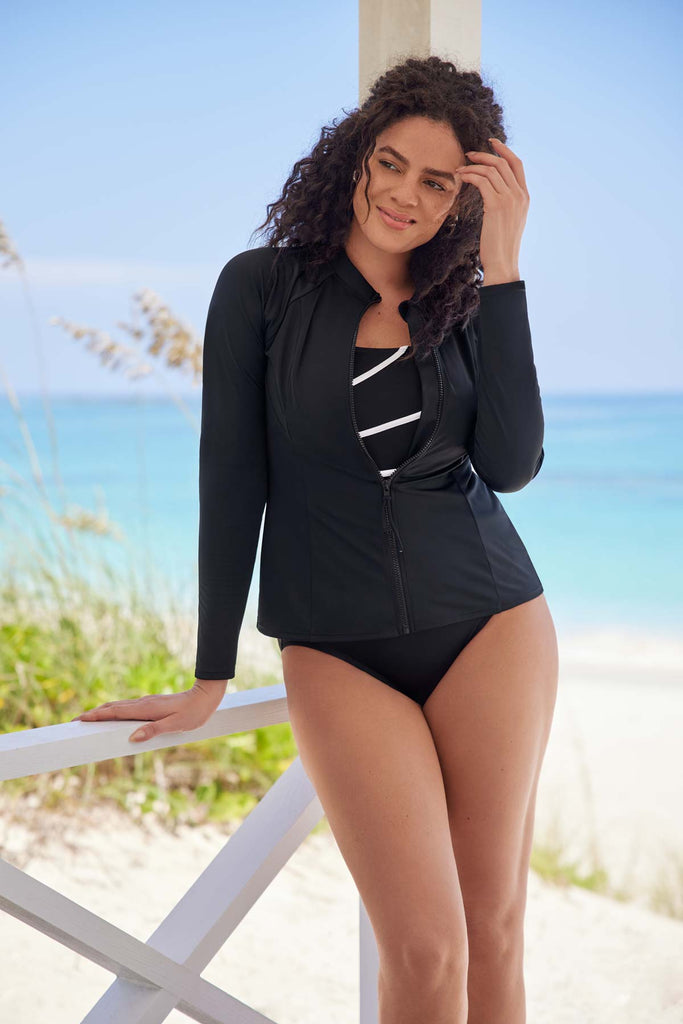 Woman near the ocean wearing an all black sun shirt with a zipper in the front