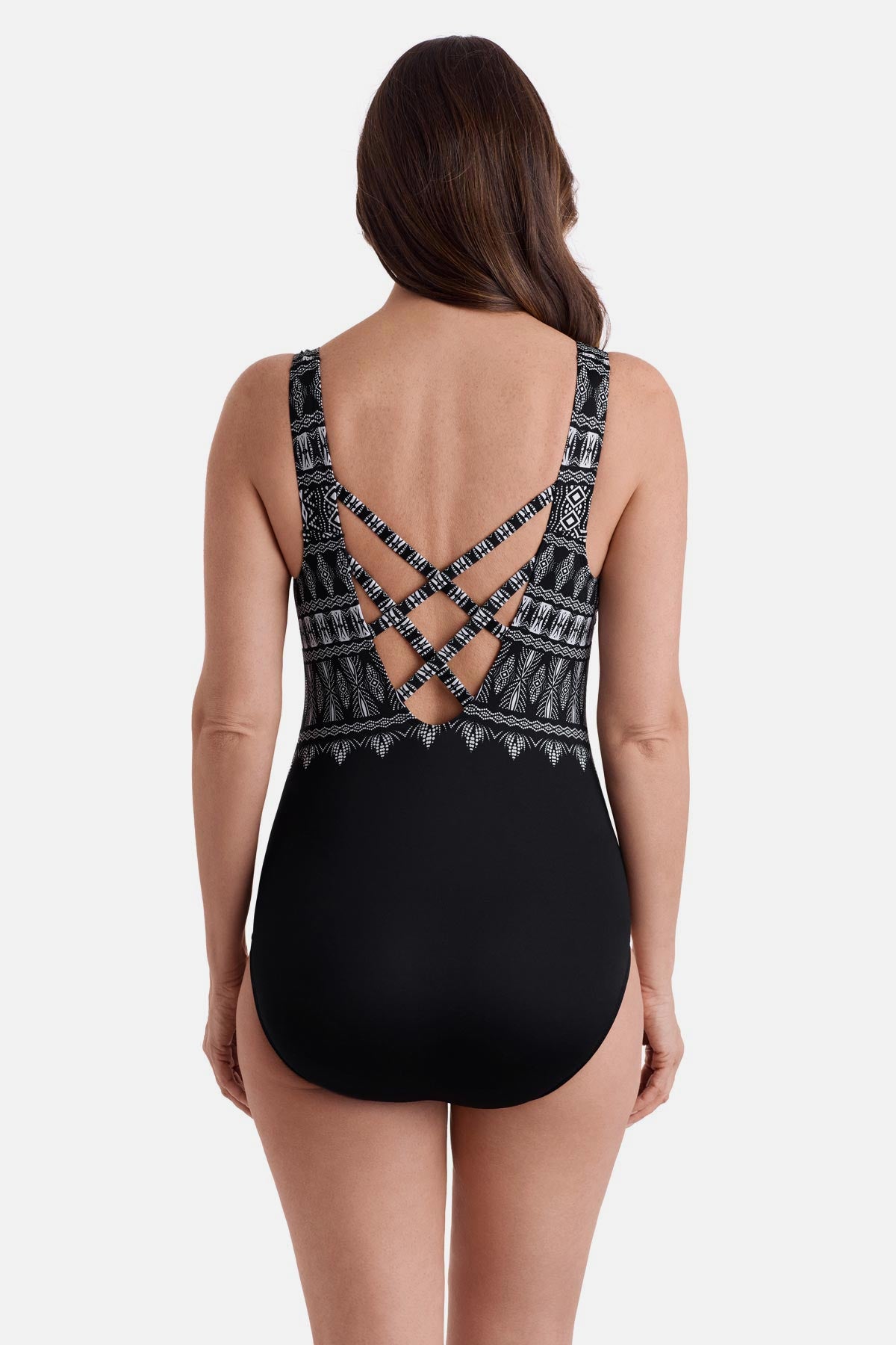 Woman turned away wearing a black and white tribal printed one-piece swimsuit with a cross back